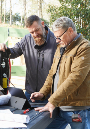 Two men discussing construction plans out of the back of a truck bed