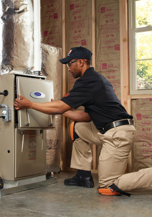 HVAC technician kneeling to fit cover on the front of an HVAC system