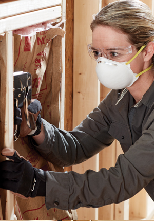 Female construction worker with a staple gun framing a room