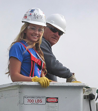 Female and Male Pro in hard hats at the top of a forklift