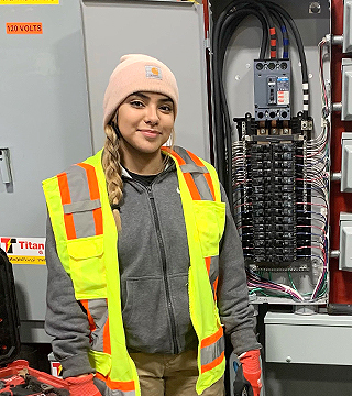 Female electrician standing in front of electrical panel and equipment