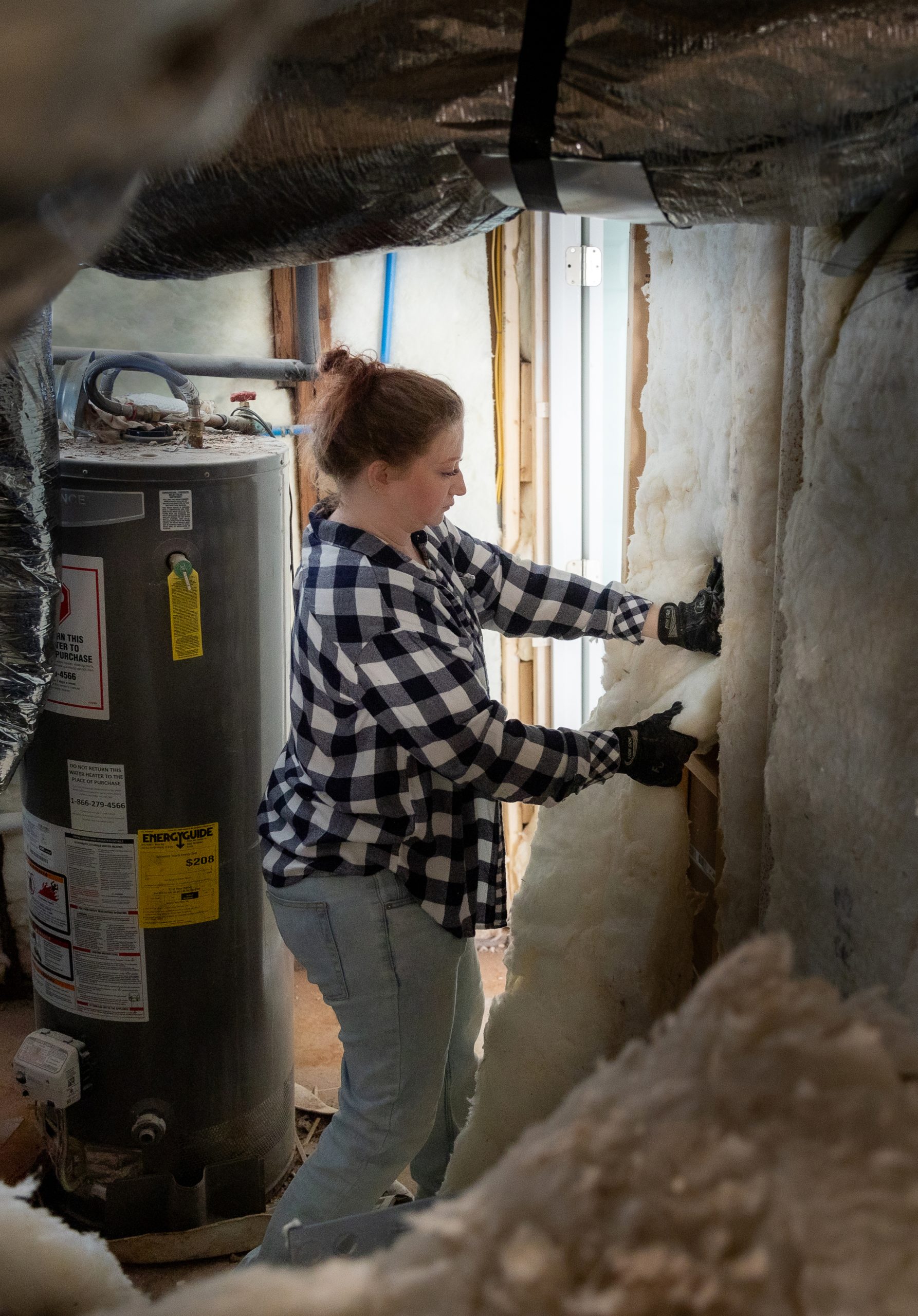 Female Pro wearing PPE removing insulation from wall