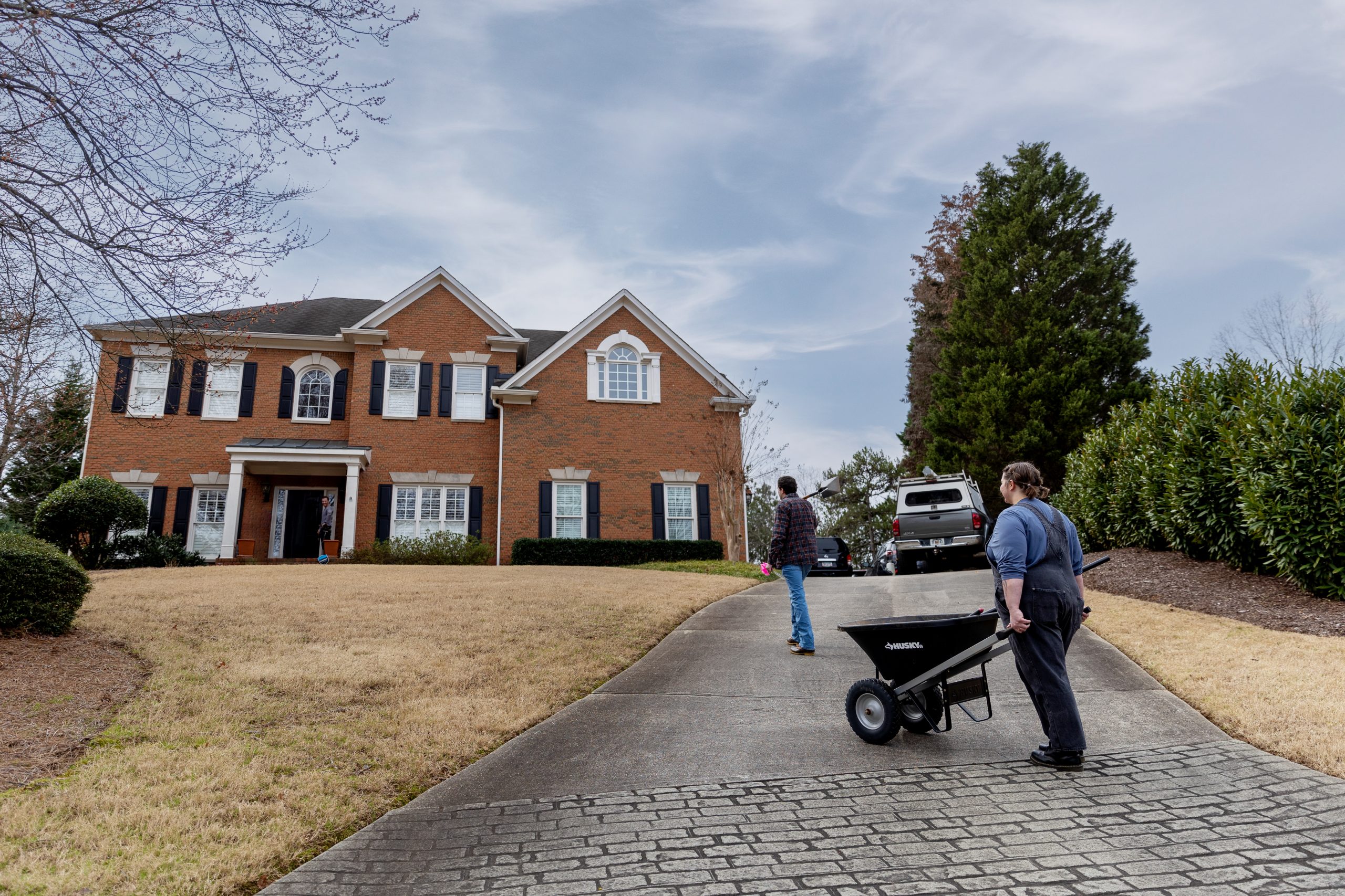 Caucasian male and female walking up a driveway with landscaping equipment