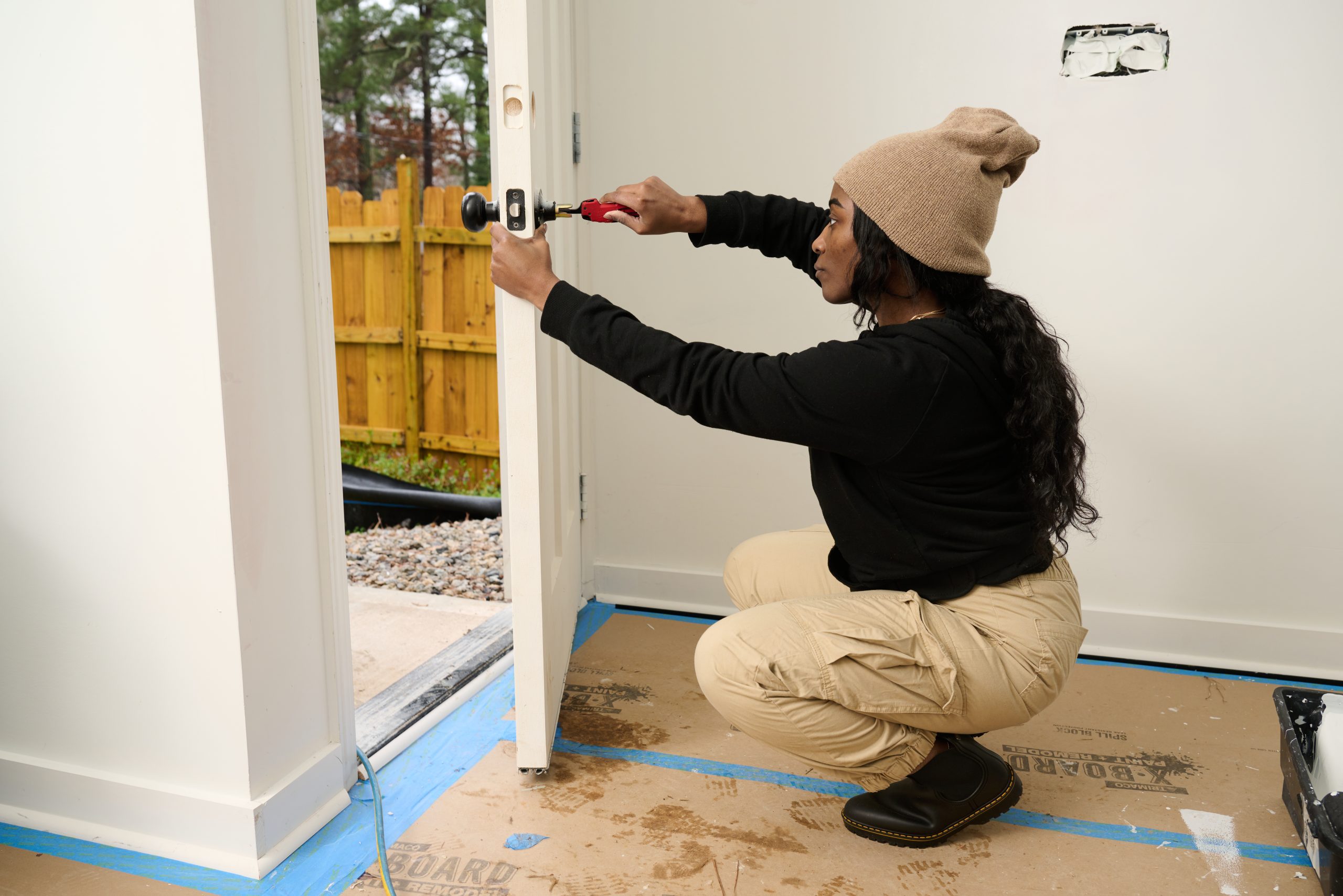 African American female squatting installing a doorknob
