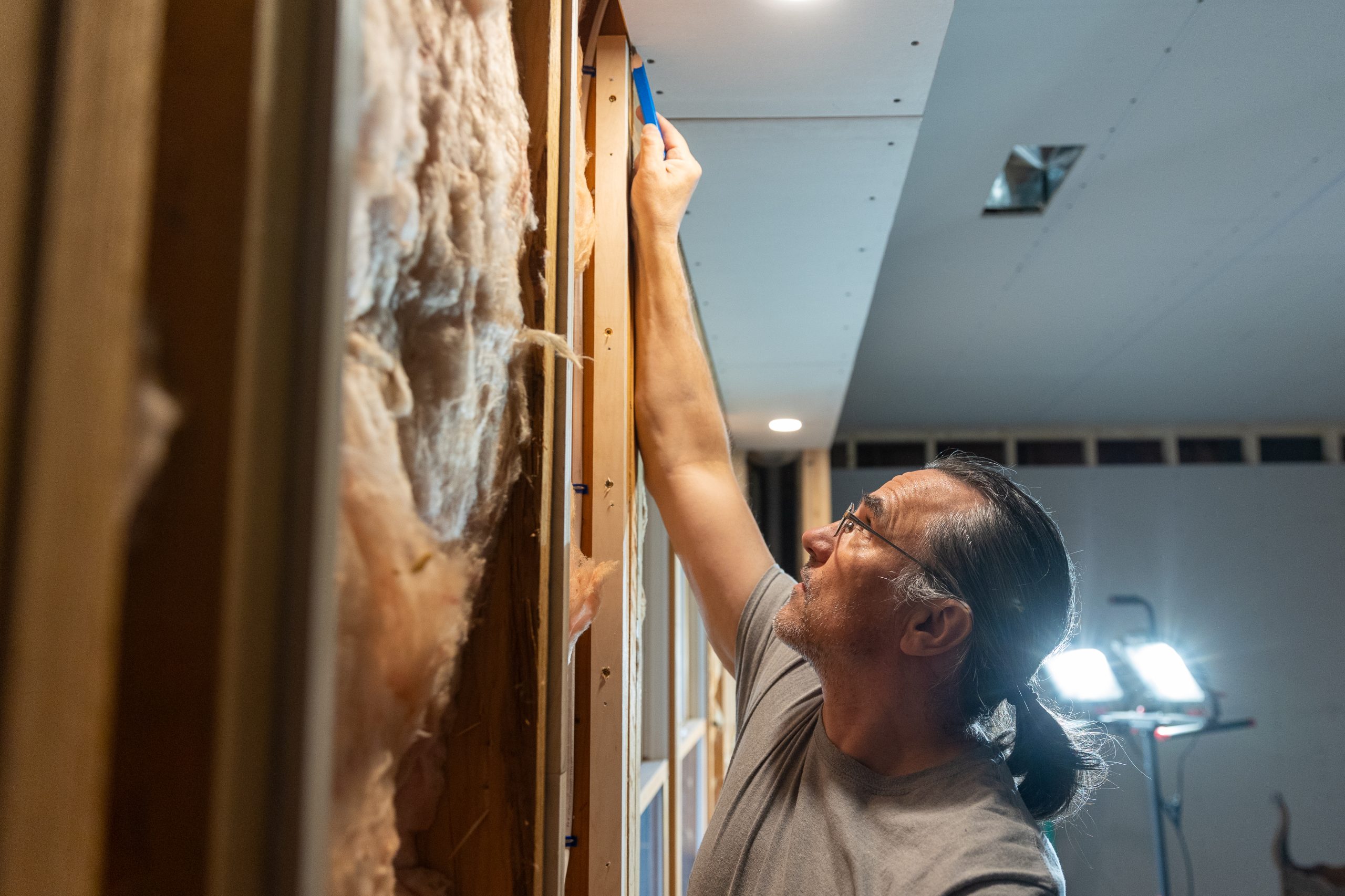 Hombre caucásico midiendo el techo para pasar el cableado eléctrico