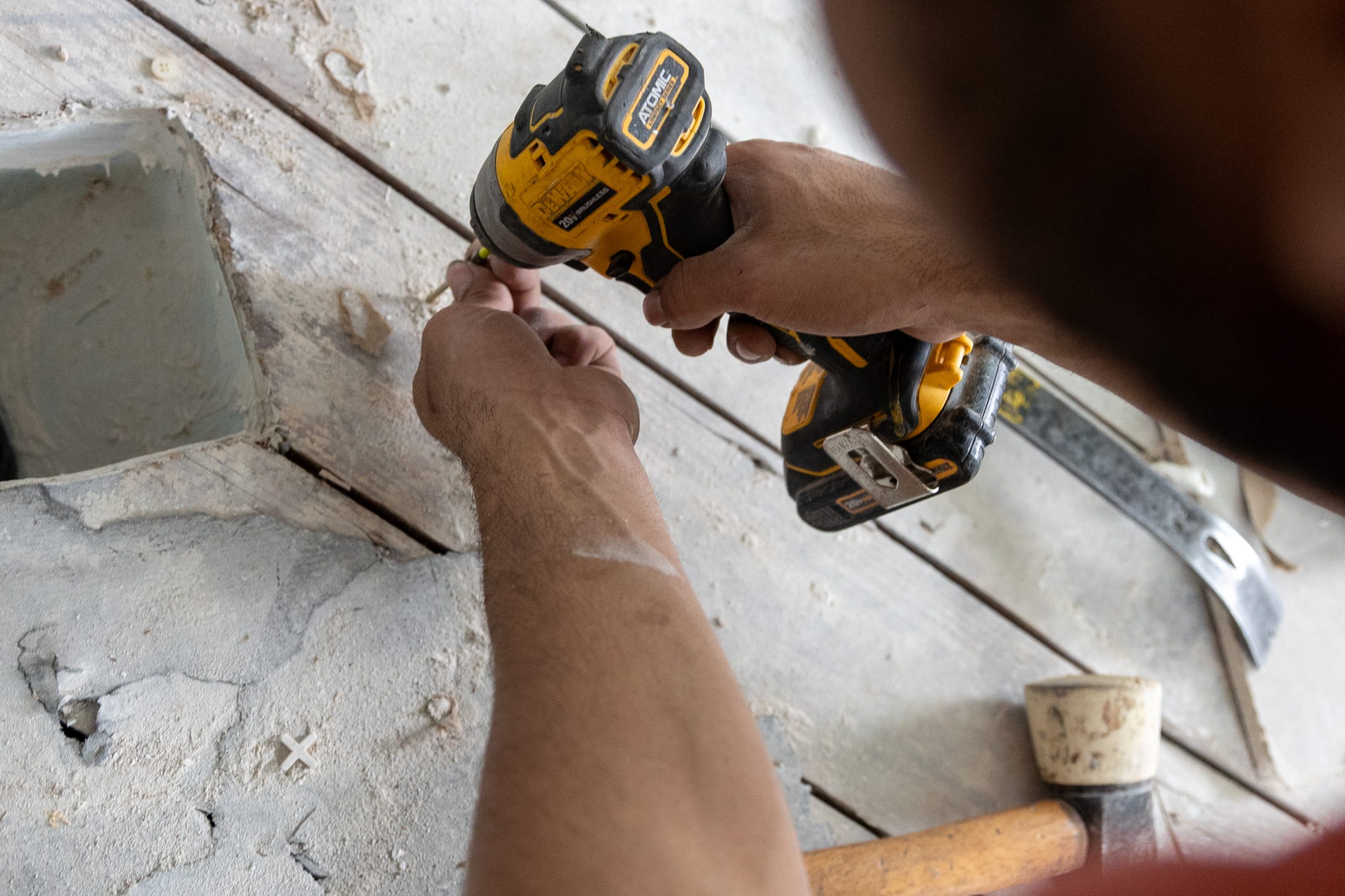 hand using a drill to screw in flooring