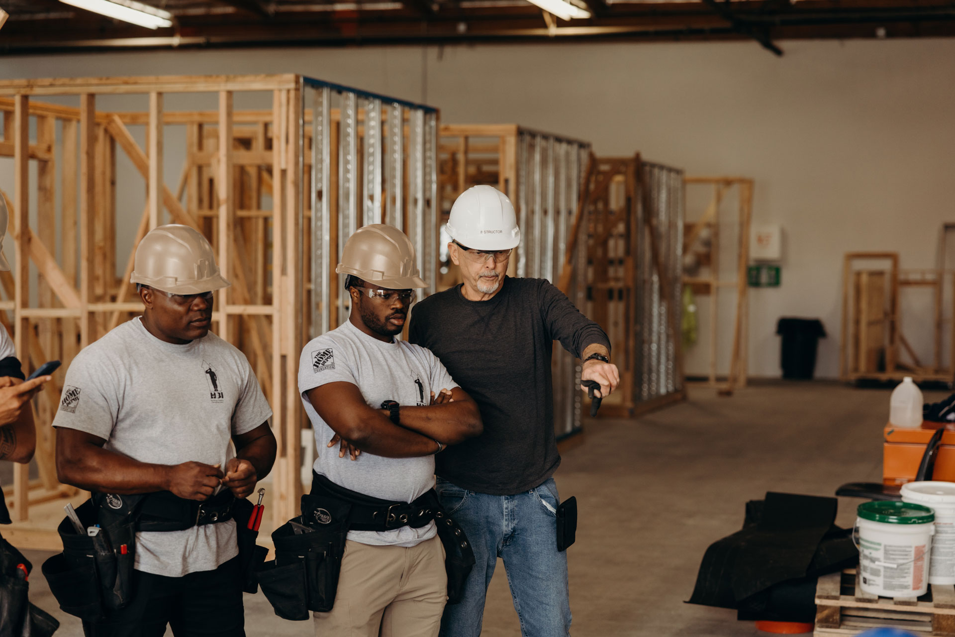 Two African American and one Caucasian male trades professionals in hard hats discussing construction plans